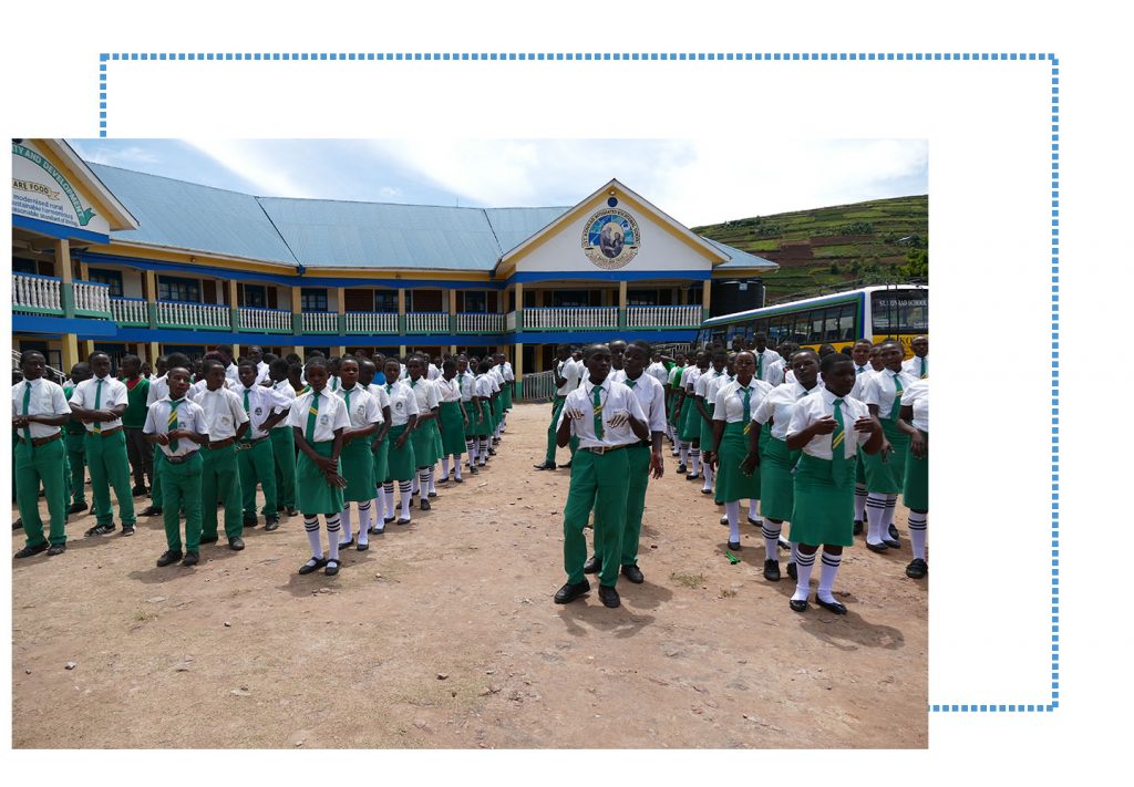 Die Schüler und Schülerinnen tanzen in ihrer Uniform vor dem Schulgebäude.